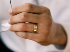 a man wearing a gold wedding band holding a wine glass with a straw in it