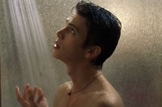 a shirtless man standing in the shower with his hands out and looking up at something