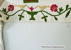 two birds on a branch with red flowers and green leaves in the center, sitting on a white table cloth