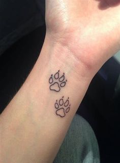 a person with a tattoo on their wrist that has two dogs paw prints on it