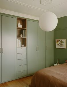 a bedroom with green painted walls and wooden flooring, built in bookshelves