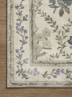 an area rug with blue and white flowers on the border, in front of a wooden floor