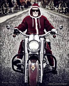 a man riding on the back of a motorcycle wearing a santa clause outfit and sunglasses