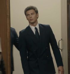 a man in a suit and tie walking into a room