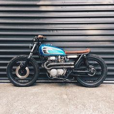 a blue and black motorcycle parked in front of a garage door