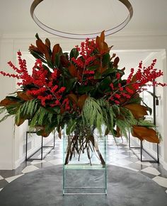 a vase filled with red flowers and greenery