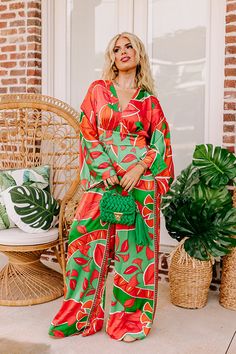 - This stunning jumpsuit is a ticket to sunshine vibes! Featuring a bold vibrant print and a chic satin finish, this trendy wide leg jumpsuit promises to steal the spotlight and keep you feeling fabulous. - Unlined material with a pink, orange, and green hued abstract botanical print with a satin finish - A v-cut neckline and a v-cut back with a tie detail - Long. loose sleeves - A waistline with an elastic back and an attached tie closure belt - A relaxed silhouette that ends in wide hemlines Trendy Wide-leg Jumpsuits And Rompers For Vacation, Trendy Wide Leg Jumpsuits And Rompers For Vacation, Trendy Wide-leg Jumpsuits For Vacation, Chic Orange Jumpsuits And Rompers For Vacation, Chic Orange Jumpsuit And Romper For Vacation, Multicolor Wide Leg Jumpsuits And Rompers For Summer, Wide Leg Multicolor Jumpsuits And Rompers For Summer, Wide Leg Multicolor Jumpsuits For Summer, Chic Printed Jumpsuits And Rompers For Brunch