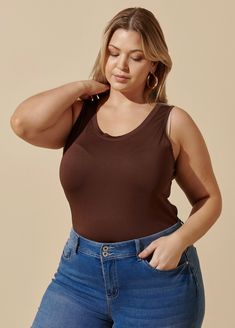 a woman in jeans and a tank top is looking down at her right hand on her hip