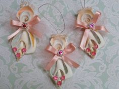 two ornaments with pink bows and pearls are hanging on a lace tablecloth covered wall