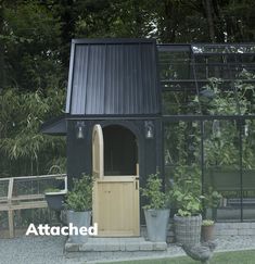 a small black house sitting in the middle of a garden