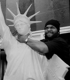 a black and white photo of a man holding the statue of liberty