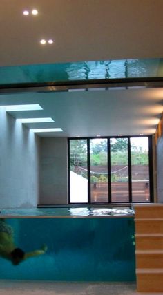 an indoor swimming pool with stairs leading up to the upper level and a man diving into it