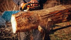 a man using a chainsaw to cut a large log