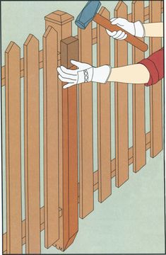 a person with gloves on holding a hammer over a wooden fence