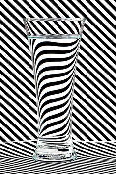 a glass filled with water sitting on top of a black and white striped table cloth