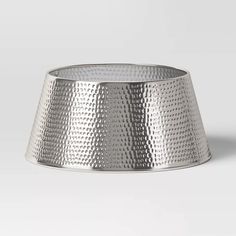 a silver metal bowl sitting on top of a white surface with no one around it