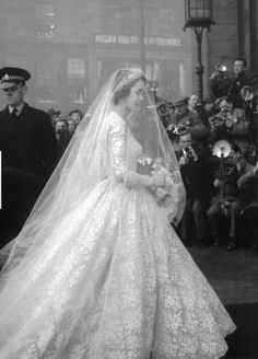 an old black and white photo of a woman in a wedding dress walking down the aisle