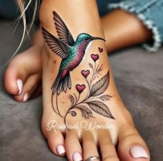 a woman's foot with a hummingbird tattoo on the top and hearts in the bottom