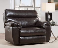 a living room with a brown recliner and a lamp on the side table in front of it