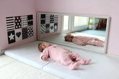 a baby laying on top of a bed in front of a mirror