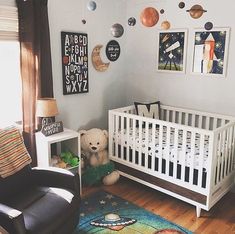 a baby's room with a white crib, black chair and pictures on the wall