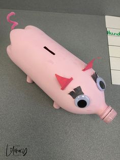 a pink plastic toy with eyes, nose and mouth sitting on top of a table