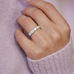 a woman's hand with a diamond ring on her left hand, wearing a purple sweater