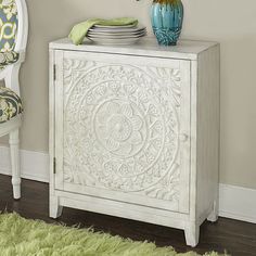 a white cabinet with plates on top and a green rug in the corner next to it