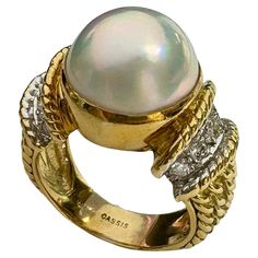 Stately and elegant, the stunning cocktail pearl and diamond ring in 18k yellow gold, by designer CASSIS. In the center sits a large white cultured pearl that measures 13.4mm. There are 5 white, round brilliant cut diamonds on either side of the pearl, with a total weight of approximately .25 cttw. Further down the sides of the ring are adorned with beautiful rope details. The pearl measures 13.4mm. Ring is stamped 18K CASSIS Ring is in wonderful pre-owned condition and sold as is. The gems are all present and securely set and gold work remains in very good order. Ring fits a size 8 finger (Can be sized by any reputable jeweler) Duties, Taxes, VAT and related import fees are not included in the price; they vary depending on shipping Luxury Yellow Gold Pearl Drop Ring, Yellow Gold Akoya Pearl Ring, Luxury Gold Akoya Pearl Ring, Luxury Yellow Gold Pearl Ring, Luxury Yellow Gold Akoya Pearl Rings, Pearl And Diamond Ring, Gold Work, Pearl Diamond, Ring Fit