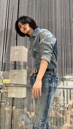 a young man standing on top of a metal rail next to a wall covered in chains