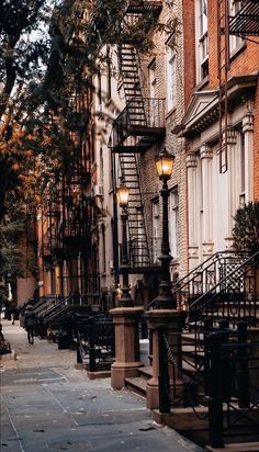 an empty city street lined with tall brick buildings and fire escape stairs on either side