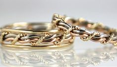 two gold wedding rings sitting on top of each other