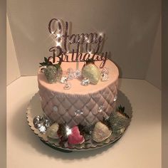 a pink birthday cake decorated with glitter and strawberries