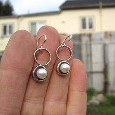 A minimal and modern look with a nod to old school pearl earrings. These sterling silver and pearl earrings are set in a modern round shadow bezel style and hang from sculptural open circles. The cultured pearl is half drilled on the bottom and glued to a sterling post soldered to the necklace for durability. You will get a lot of compliments when wearing this mini art piece. To see all my pearl jewelry go here: https://www.etsy.com/shop/marmarModern?ref=seller-platform-mcnav&section_id=1328 Minimalist Round Pearl Drop Earrings, Modern White Pierced Pearl Earrings, White Modern Pierced Pearl Earrings, Modern Pearl Earrings With Ear Wire For Everyday, Modern Everyday Pearl Drop Earrings, Modern Round Pearl Earrings, Minimalist Round Pearl Earrings With Ear Wire, Everyday Sterling Silver Pearl Earrings, Modern Everyday Dangle Pearl Earrings