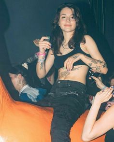 a woman sitting on top of an orange couch holding a cell phone in her hand