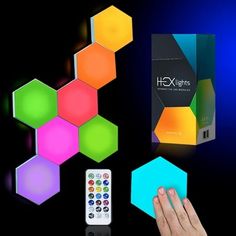 a person holding a remote control in front of some colorful hexagons on a black background