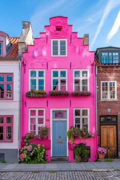 a pink house with many windows and flowers on the front door is painted bright pink