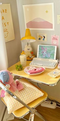 a desk with a laptop, mouse and stuffed animal sitting on top of it in front of a yellow chair