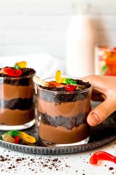 two desserts on a plate being held by someone's hand with candy in the middle