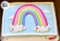 a birthday cake decorated with a rainbow and clouds