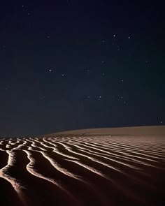 the night sky is lit up by stars above sand dunes