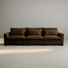 a brown couch sitting on top of a carpeted floor next to a white wall