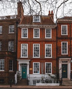 an old brick building with many windows and steps leading up to the front door is shown