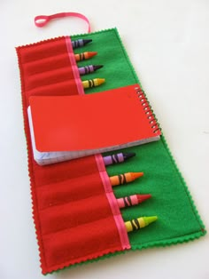 two notebooks with crayons on them are sitting next to each other, one is red and the other is green