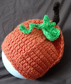 an orange crocheted hat sitting on top of a white ball