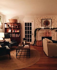 a living room filled with furniture and a fire place next to a book shelf on top of a hard wood floor