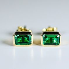 Elevate your style with our 14k Gold Bezel Emerald Cut Emerald Stud Earrings, perfect for adding a touch of sophistication and elegance to any outfit. These emerald cut emerald stud earrings are the perfect size for everyday wear or special occasions, and their brilliant green color is sure to catch the eye and make a statement. These exquisite studs feature genuine emerald gemstones that are lab-grown for a sustainable and ethical choice. Unlike simulated or CZ stones, lab-grown emeralds are id Emerald Studs, 20th Anniversary Gifts, Emerald Stud Earrings, Earrings Emerald, Emerald Ring Gold, Emerald Earrings Studs, Birthstone Earrings, Solid Gold Earrings, May Birthstone