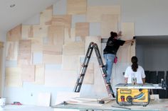 two people are working on wood panels in a room that is being renovated with construction equipment