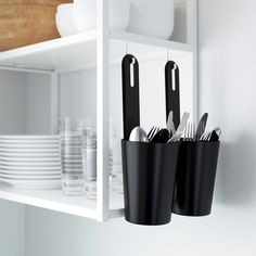 black utensils and silverware are in cups on the shelf