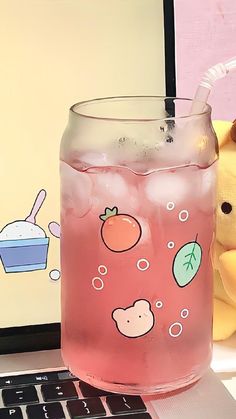 a pink drink sitting on top of a laptop computer next to a teddy bear and stuffed animal